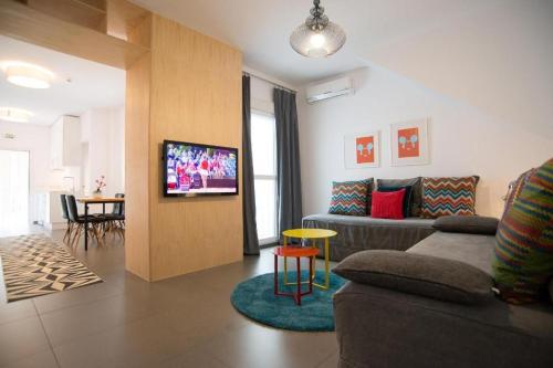 a living room with a couch and a tv on a wall at Chipibeach, Hostal Boutique in Chipiona