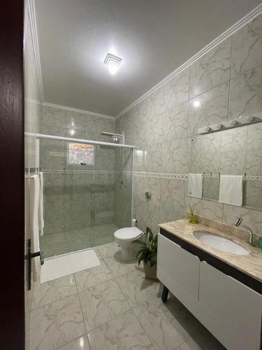 a bathroom with a shower and a toilet and a sink at Recanto Wunderwald Casa Pomerode in Pomerode