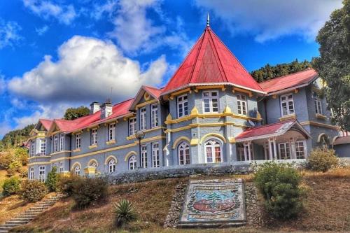 a large building with a red roof on a hill at Damfu Basera Homestay in Kurseong