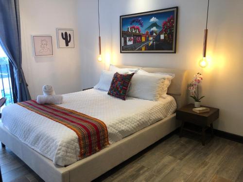 Schlafzimmer mit einem Bett mit weißer Bettwäsche und Kissen in der Unterkunft L1B 202 - Boutique apartamento en Cayalá para 4 huéspedes in Guatemala