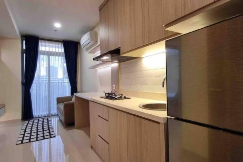 a kitchen with a refrigerator and a sink at Apt Pejaten Park 1BR Khaki with SmartTv and Pool in Jakarta