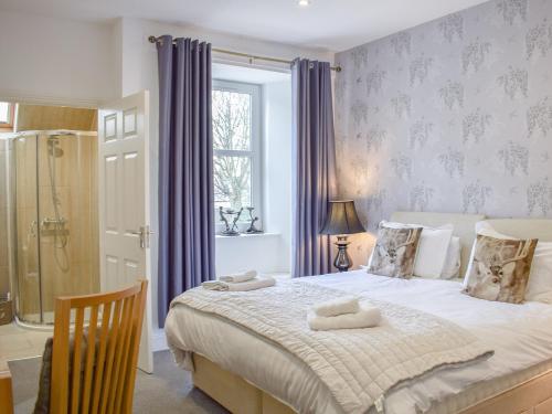 a bedroom with a large bed with blue curtains at Fionas Cottage in Crieff
