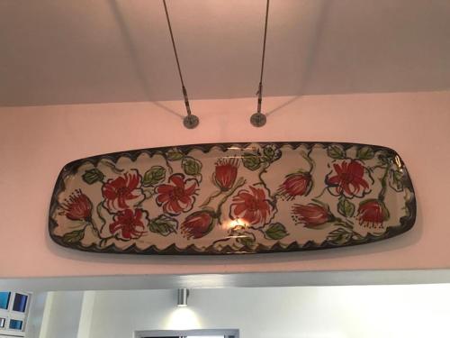 a suitcase hanging on a wall with flowers on it at La Maison Bleue, luxury self-catering villa. in Langebaan