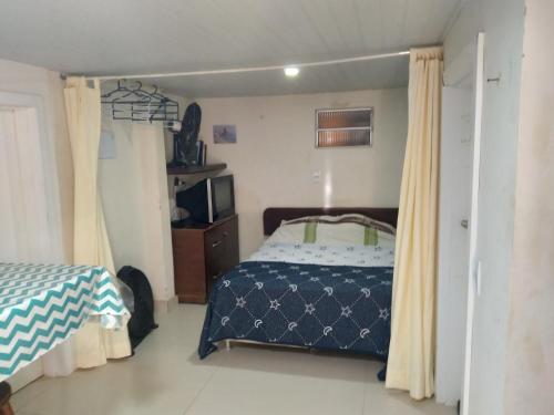 1 dormitorio con 1 cama, TV y cortinas en Sossego da ilha 02, en Florianópolis