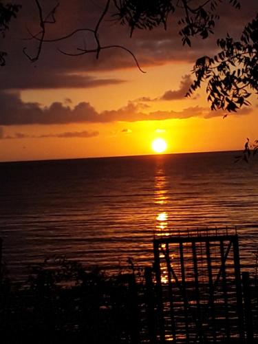 a sunset over the ocean with the sun setting at MG beach house in Tanga