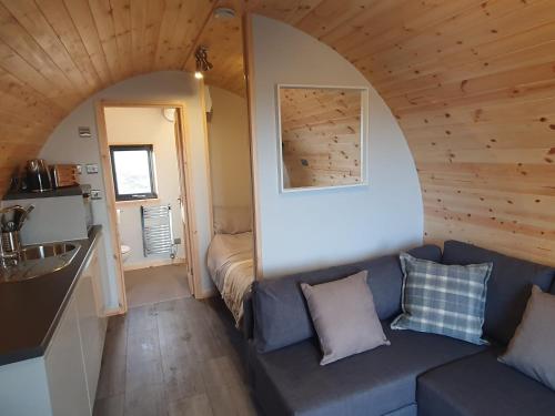 een woonkamer met een bank in een tiny house bij Grimsay Glamping, North Uist - Pod Ruadh in Rossinish