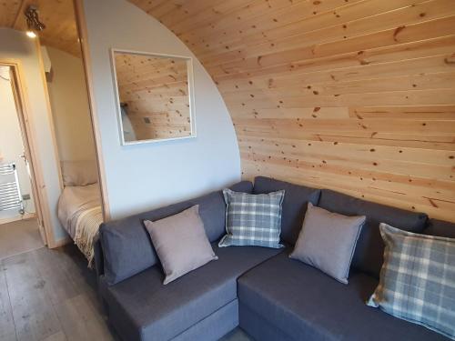 a living room with a blue couch with pillows at Grimsay Glamping, North Uist - Pod Ruadh in Rossinish