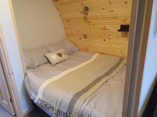 a small bed in a room with a wooden wall at Grimsay Glamping, North Uist - Pod Ruadh in Rossinish