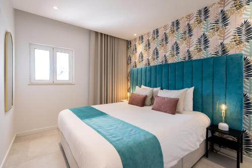 Schlafzimmer mit einem großen Bett mit blauem Kopfteil in der Unterkunft Sunny in Albufeira