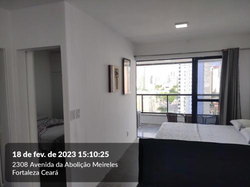 a bedroom with a bed and a large window at Via Venetto Flat Fortaleza Bera mar Meireles in Fortaleza
