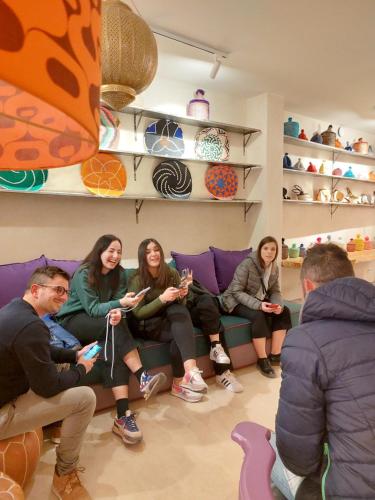 een groep mensen die op een bank zitten en een videospel spelen bij Miostello Lifestyle Hostel Marrakech in Marrakesh