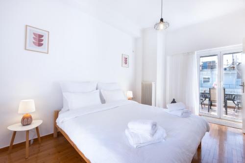 a white bedroom with a large white bed and a window at Loft Apt with Acropolis View in Athens