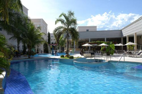 - une grande piscine dans un complexe avec des palmiers dans l'établissement Otimo apto c piscina e Wi Fi em Caldas Novas GO, à Caldas Novas