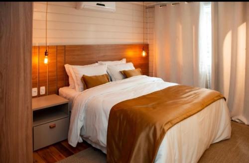 烏魯比西的住宿－Chalé Top banheira e lareira，一间卧室配有一张大床和木制床头板