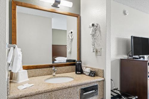 Bend Inn & Suites في بيند: حمام مع حوض ومرآة
