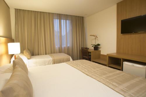 a hotel room with two beds and a flat screen tv at Casablanca Center Hotel in Petrópolis