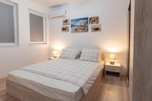a white bedroom with a bed and two lamps on tables at Ioama Island in Burgas City