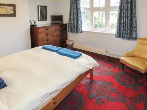 a bedroom with a bed and a chair and a window at Moor House in Tirril