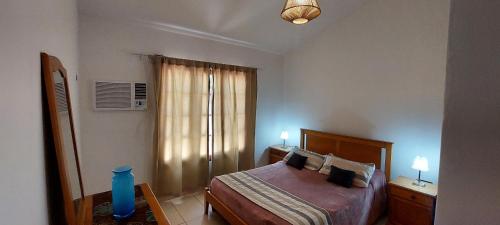 1 dormitorio con 1 cama con 2 lámparas y una ventana en Departamento Cumbre Alta en Villa Dolores