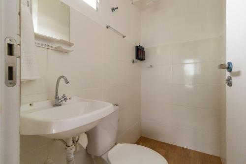 a white bathroom with a sink and a toilet at Wafeh Pampulha Suítes in Belo Horizonte