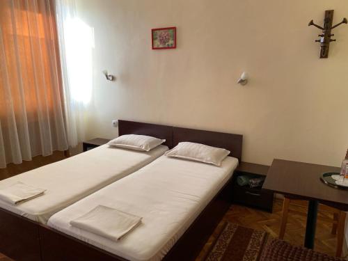 two beds in a room with a cross on the wall at Family Hotel "May" in Petrich