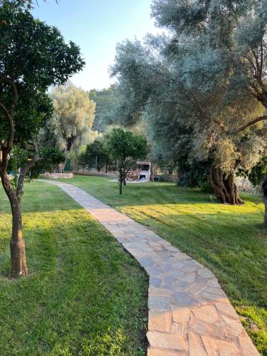 a stone path through a park with trees at Elleria's House in Lefkada Town