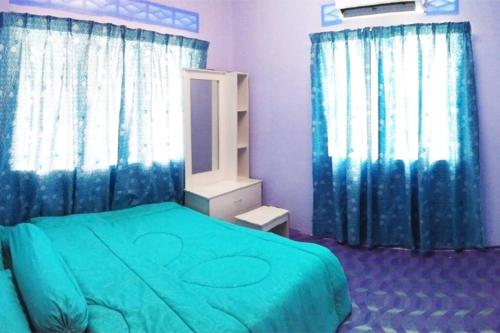 a bedroom with a green bed and blue curtains at Tatami Homestay UIA Gombak in Kuala Lumpur