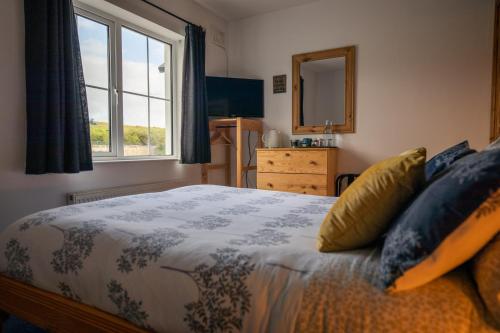 a bedroom with a bed and a window and a mirror at The Sleepy Leprechaun in Doolin