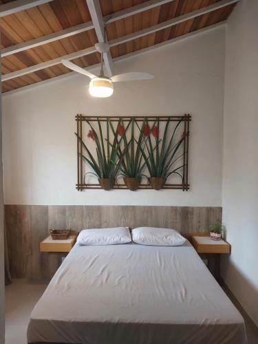 a bedroom with a bed with two plants on the wall at Recanto da Praia Kitnetes in Caraguatatuba