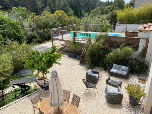 un patio con sombrilla, sillas y piscina en Rez-de-villa proche de la mer - Villa Temana, en Saint-Cyr-sur-Mer