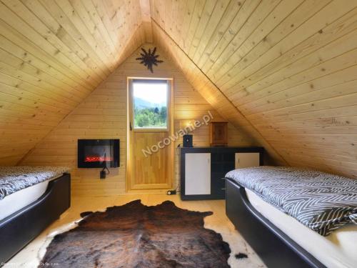 a room with two beds in a wooden room with a window at Słoneczna Osada Domki w górach na wyłączność in Kowary