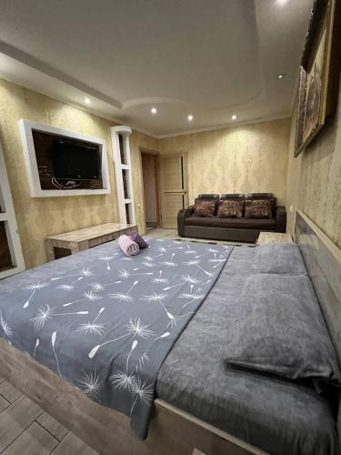1 dormitorio con 1 cama grande y edredón azul en LUX и комфорт, en Shymkent