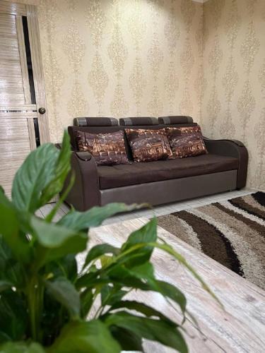 un sofá negro en una sala de estar con una planta en LUX и комфорт, en Shymkent