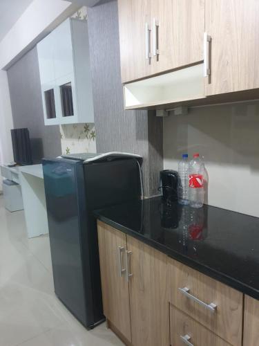 cocina con encimera negra y nevera en Galeri Ciumbuleuit Apartment 2 By Gezonder, en Bandung