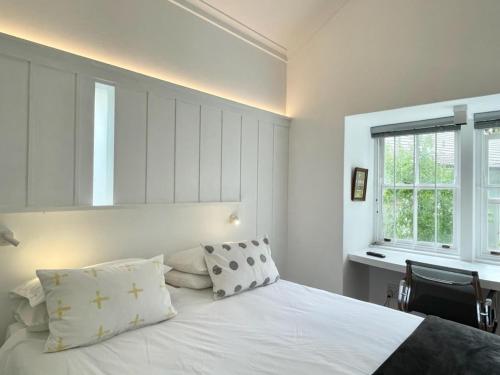 um quarto com uma cama branca com almofadas e uma janela em Guest House at 118 by PWM Architects em Joanesburgo