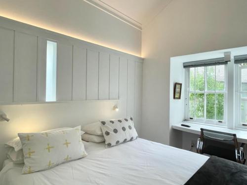 a bedroom with a white bed with pillows and a window at Guest House at 118 by PWM Architects in Johannesburg