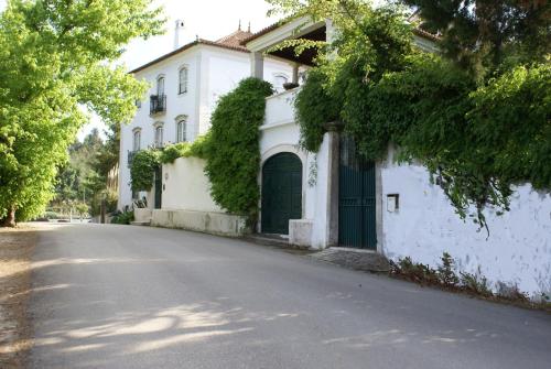 a white house with a green door on a street at Quinta de São Lourenço in São Lourenço do Bairro