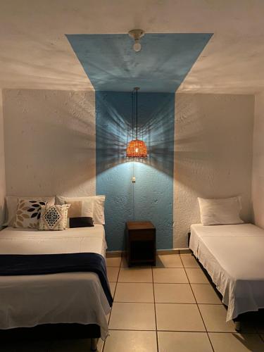 een slaapkamer met 2 bedden en een lampje aan de muur bij THIS IS COLOMBIA HOSTEL in San Gil