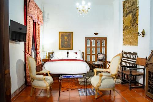 a bedroom with a bed and two chairs at Hotel Casa de la Luz in Bogotá