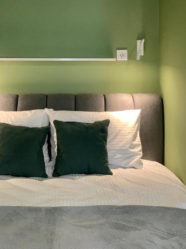 a bed with green walls and white sheets and pillows at Апартаменти-студія, дизайнерський ремонт, ЦЕНТР, біля Либідь Плаза in Khmelʼnytsʼkyy