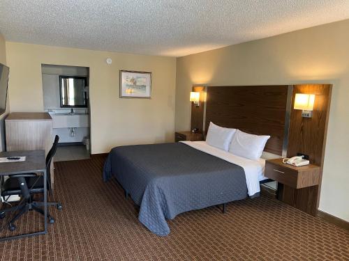 a hotel room with a bed and a desk at Red Carpet Inn Kinston in Kinston