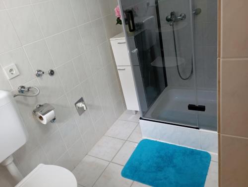 baño con ducha y alfombra azul en Apartmani Trubi en Vodice