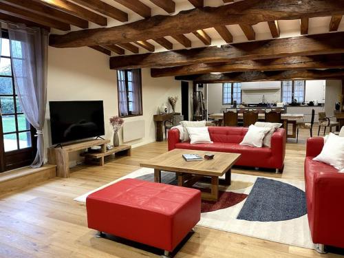 a living room with two red couches and a tv at Maison haut de gamme proche de Deauville-Trouville in Les Authieux-sur-Calonne