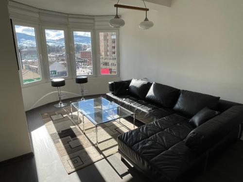 uma sala de estar com um sofá de couro preto e uma mesa de vidro em SleepInNP em Novi Pazar
