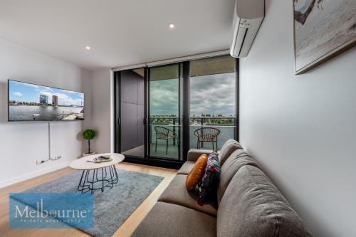 a living room with a couch and a large window at Melbourne Private Apartments - Collins Wharf Waterfront, Docklands in Melbourne