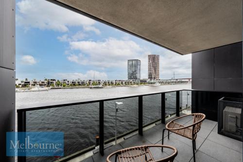 a balcony with two chairs and a view of the water at Melbourne Private Apartments - Collins Wharf Waterfront, Docklands in Melbourne