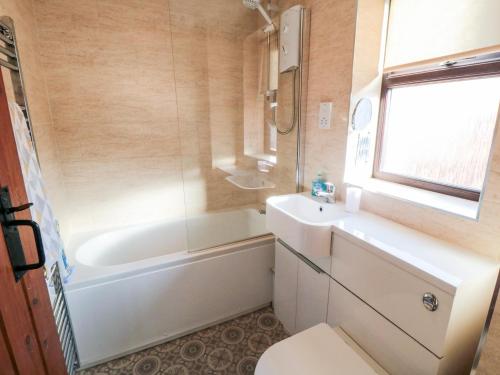 een badkamer met een bad, een toilet en een wastafel bij Cha Cha's Cottage in Whitby