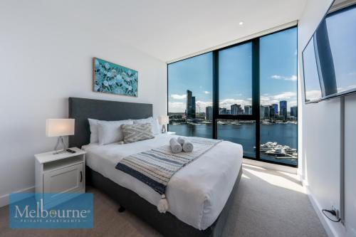 um quarto com uma cama e uma grande janela em Melbourne Private Apartments - Collins Wharf Waterfront, Docklands em Melbourne