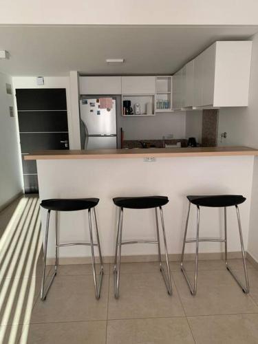 a kitchen with three bar stools in front of a counter at Hermoso depto en excelente ubicacion in Puerto Madryn