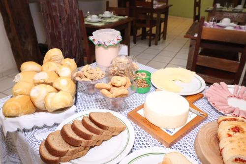 a table with bread and plates of food on it at Pousada Maria Bonita in Macacos